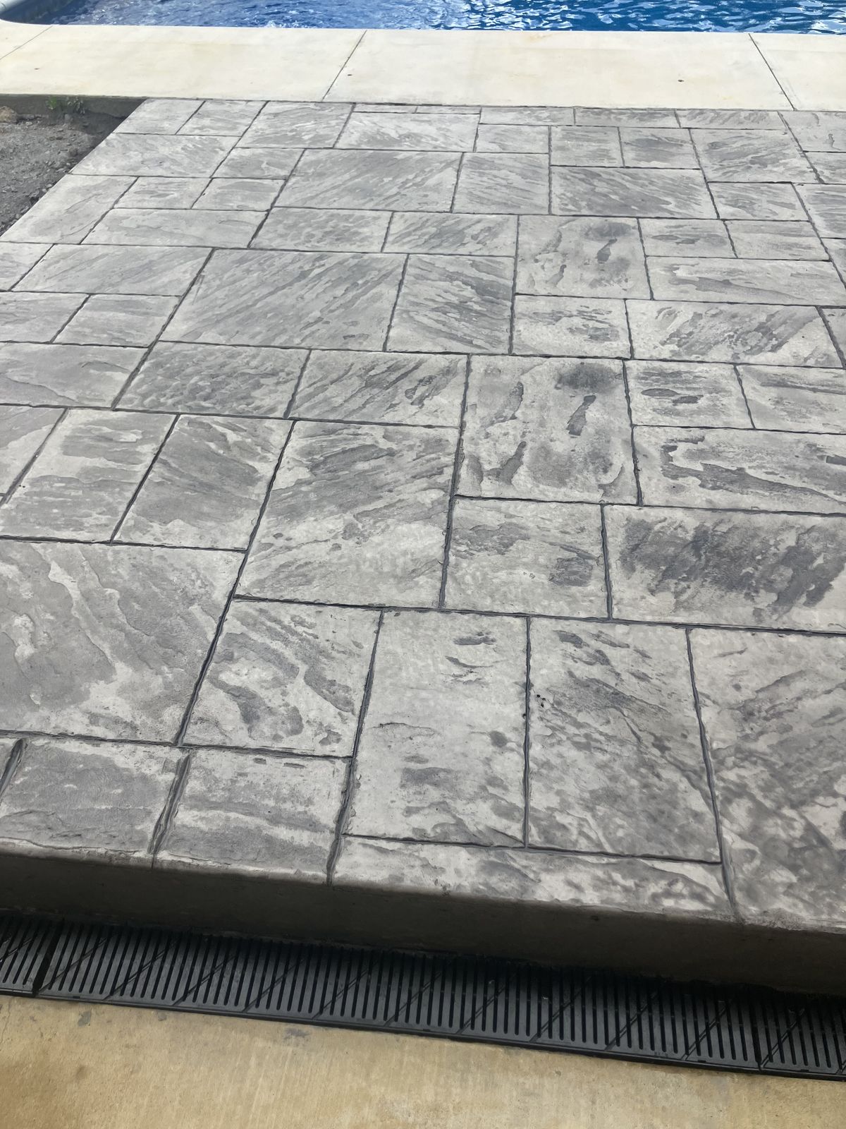 Stamped concrete pool deck edge with drain in Arkansas